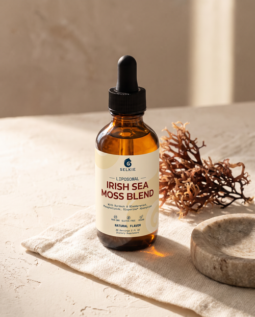 Selkie Irish Sea Moss dropper bottle beside dried Chondrus crispus seaweed on linen in morning light