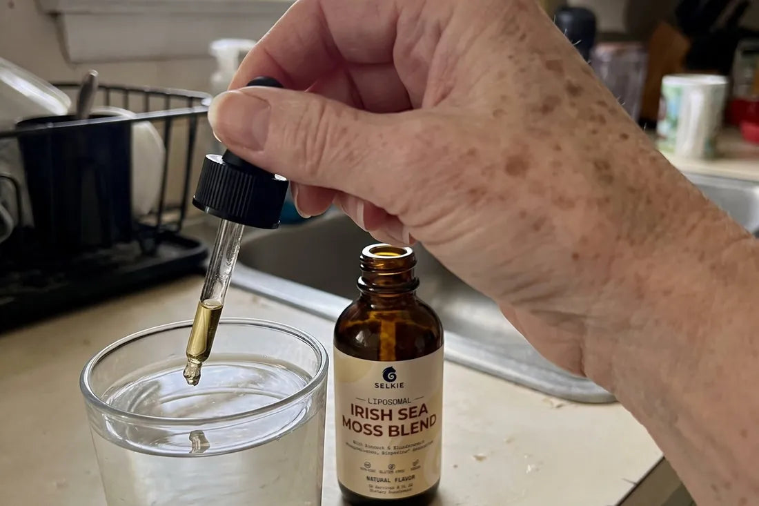 A hand holding the Selkie dropper over a glass on a kitchen counter