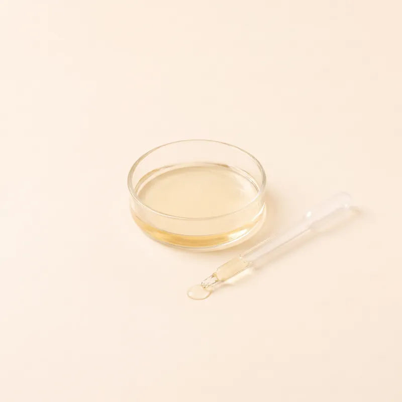 A glass pipette beside a dish of pale golden liquid